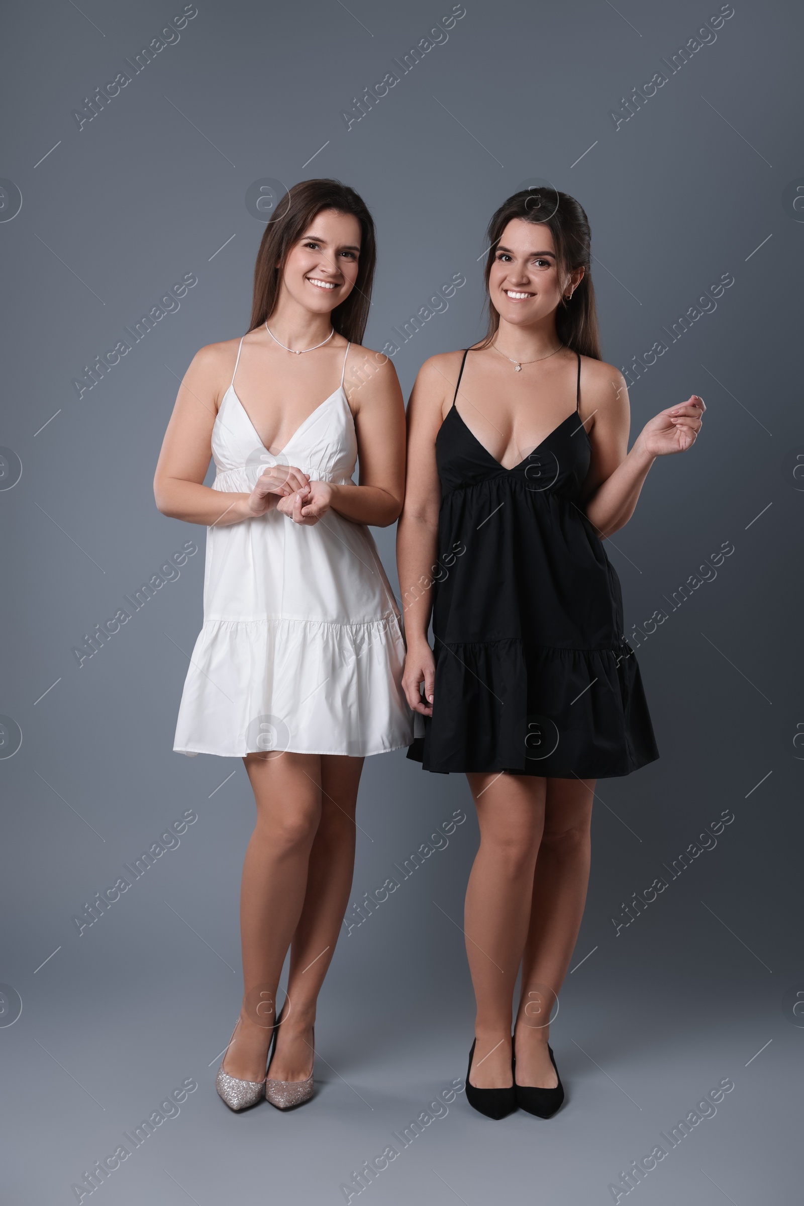 Photo of Portrait of beautiful twin sisters on grey background