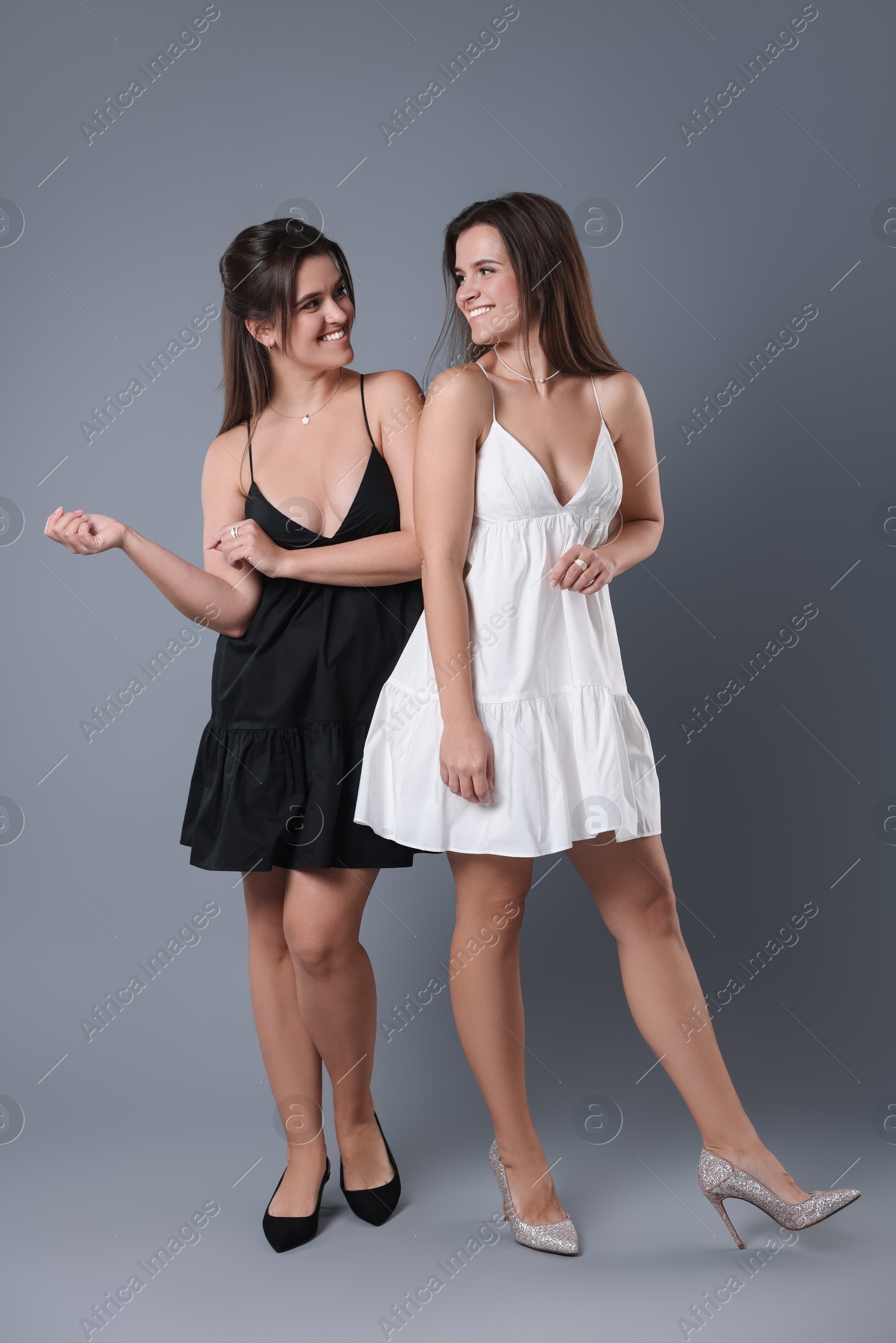 Photo of Portrait of beautiful twin sisters on grey background