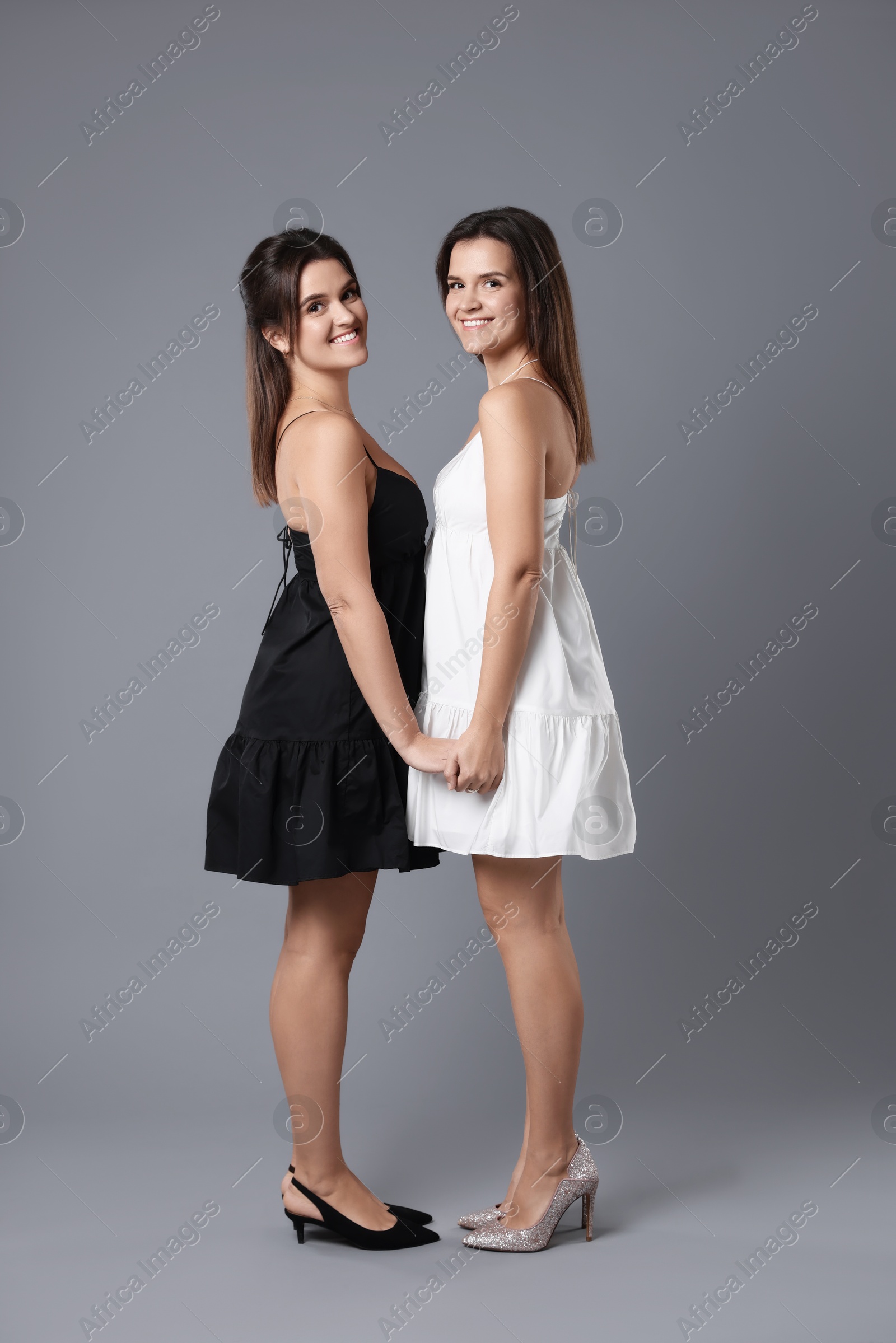 Photo of Portrait of beautiful twin sisters on grey background