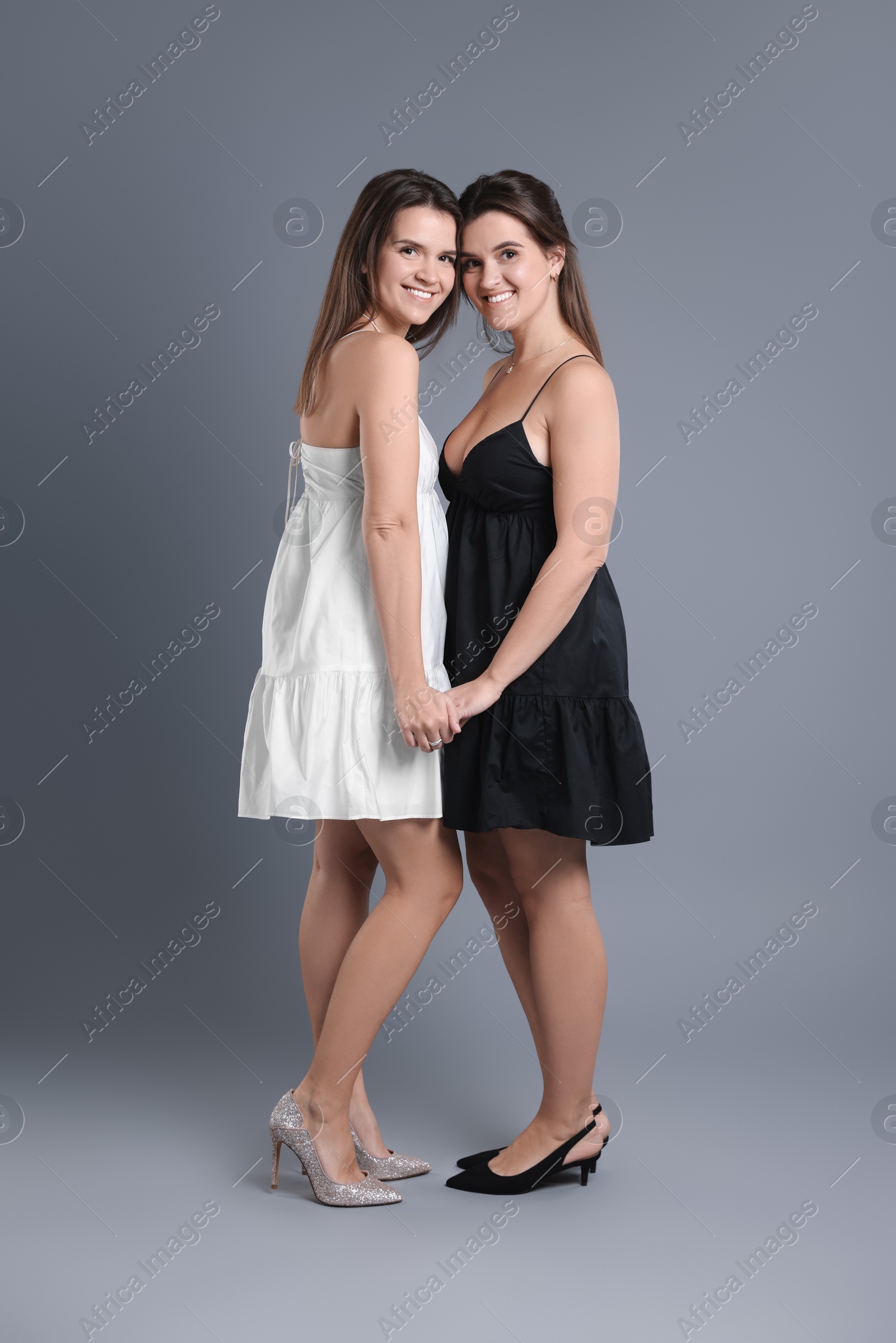 Photo of Portrait of beautiful twin sisters on grey background