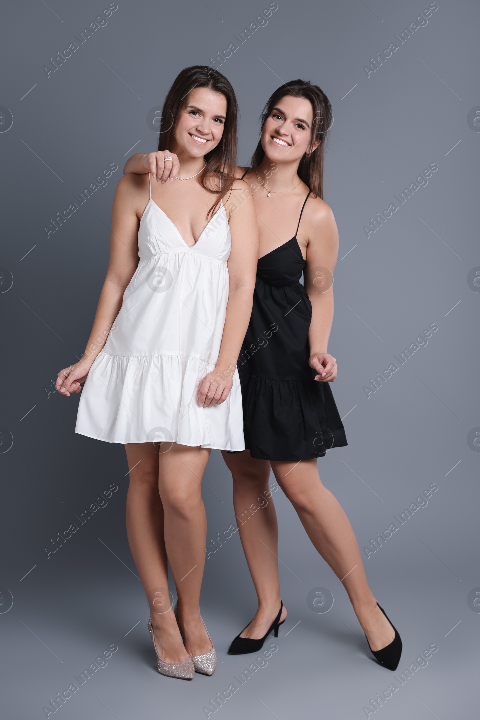 Photo of Portrait of beautiful twin sisters on grey background