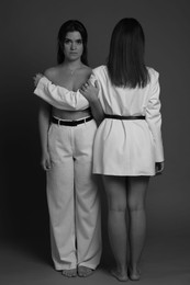 Photo of Portrait of beautiful twin sisters on dark background. Black and white effect