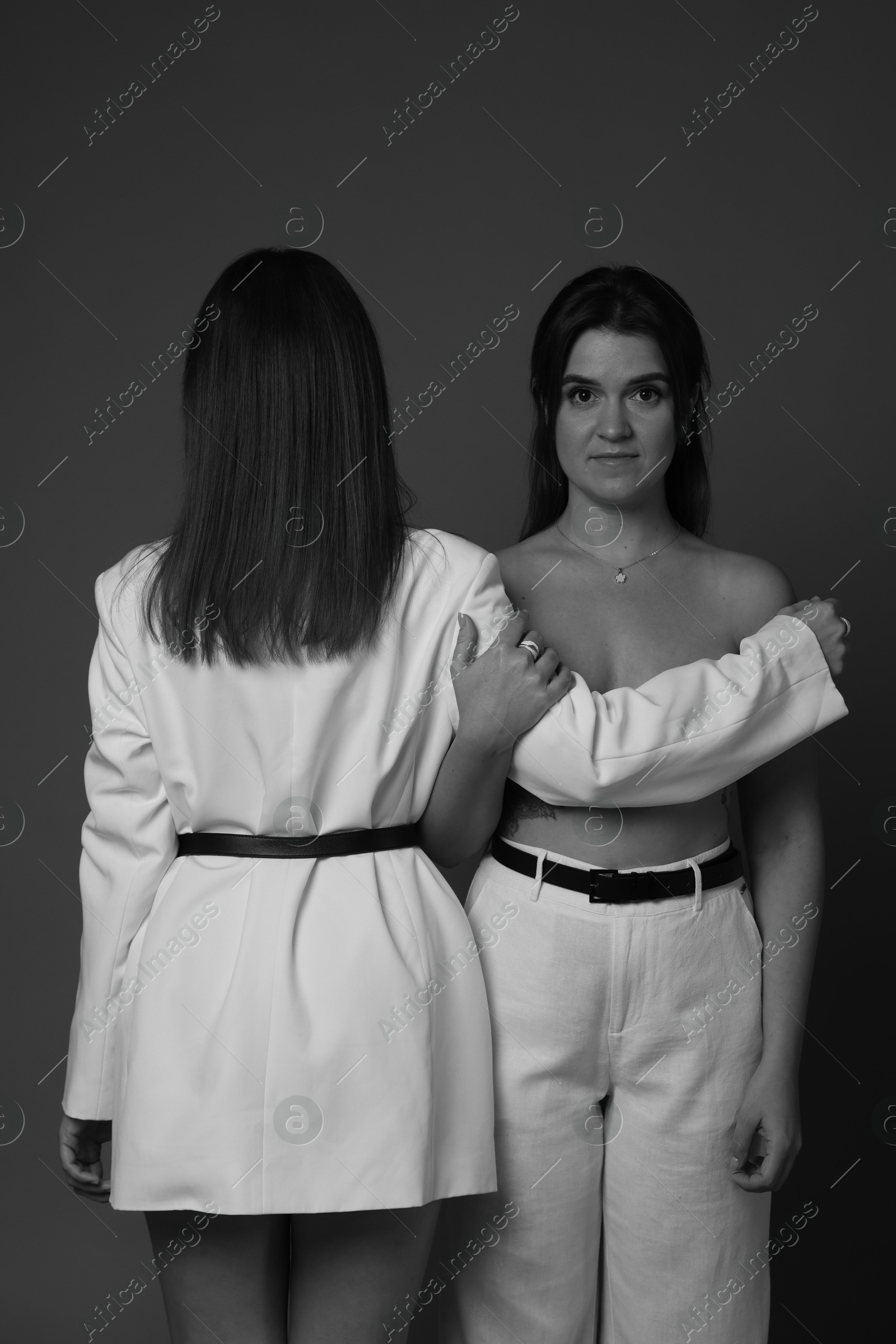 Photo of Portrait of beautiful twin sisters on dark background. Black and white effect