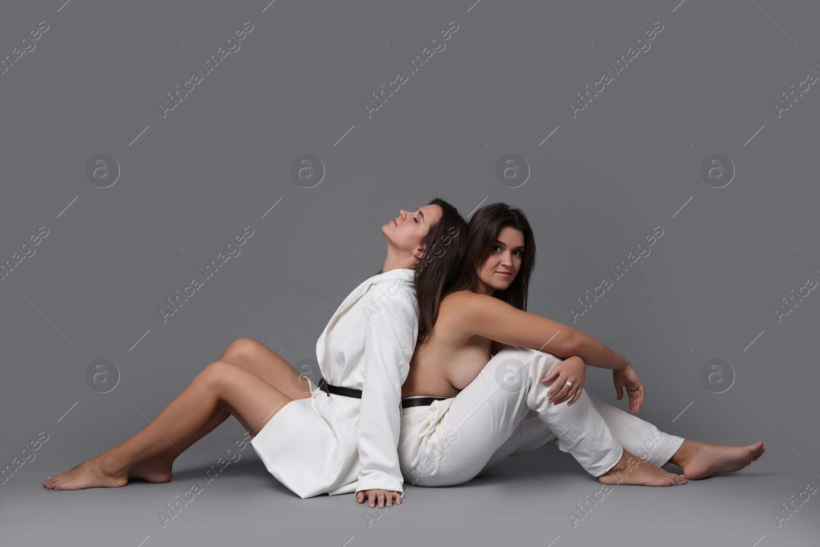 Photo of Portrait of beautiful twin sisters on grey background