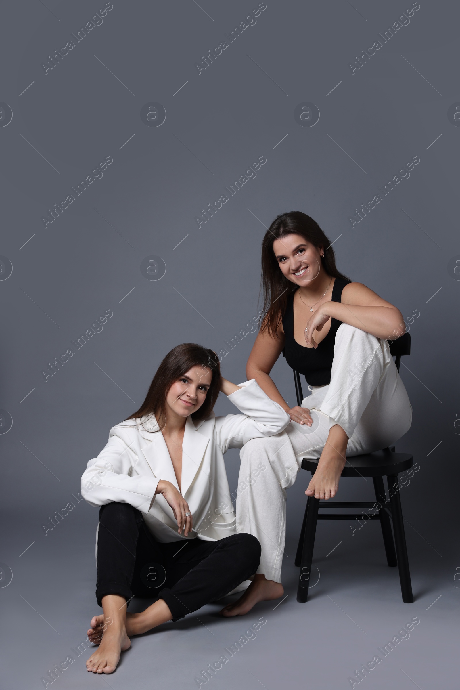 Photo of Portrait of beautiful twin sisters on grey background