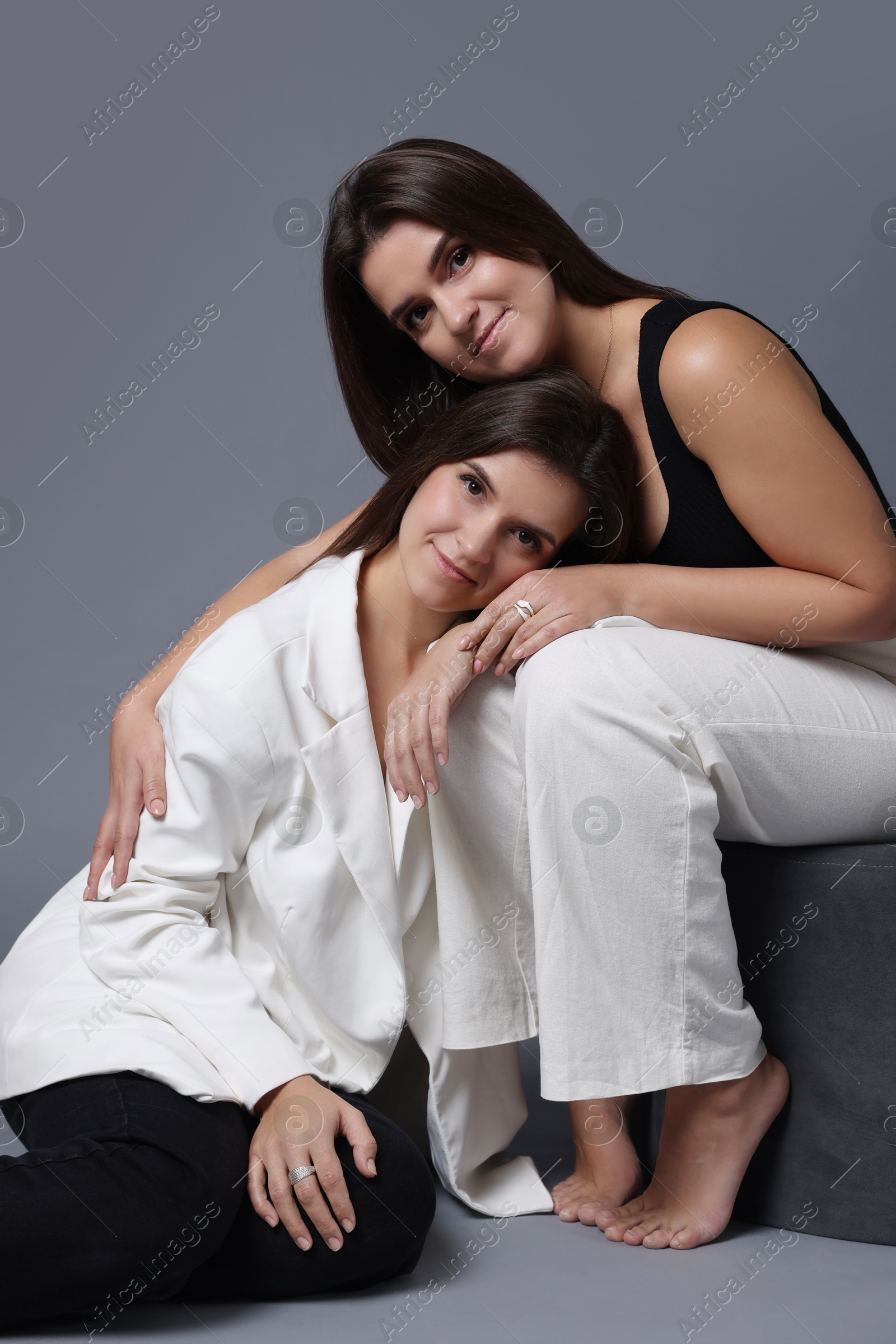 Photo of Portrait of beautiful twin sisters on grey background