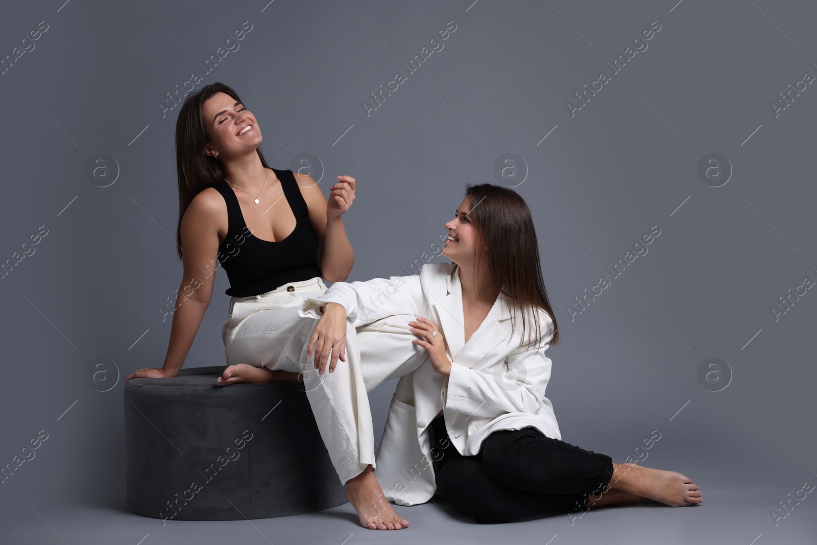 Photo of Portrait of beautiful twin sisters on grey background