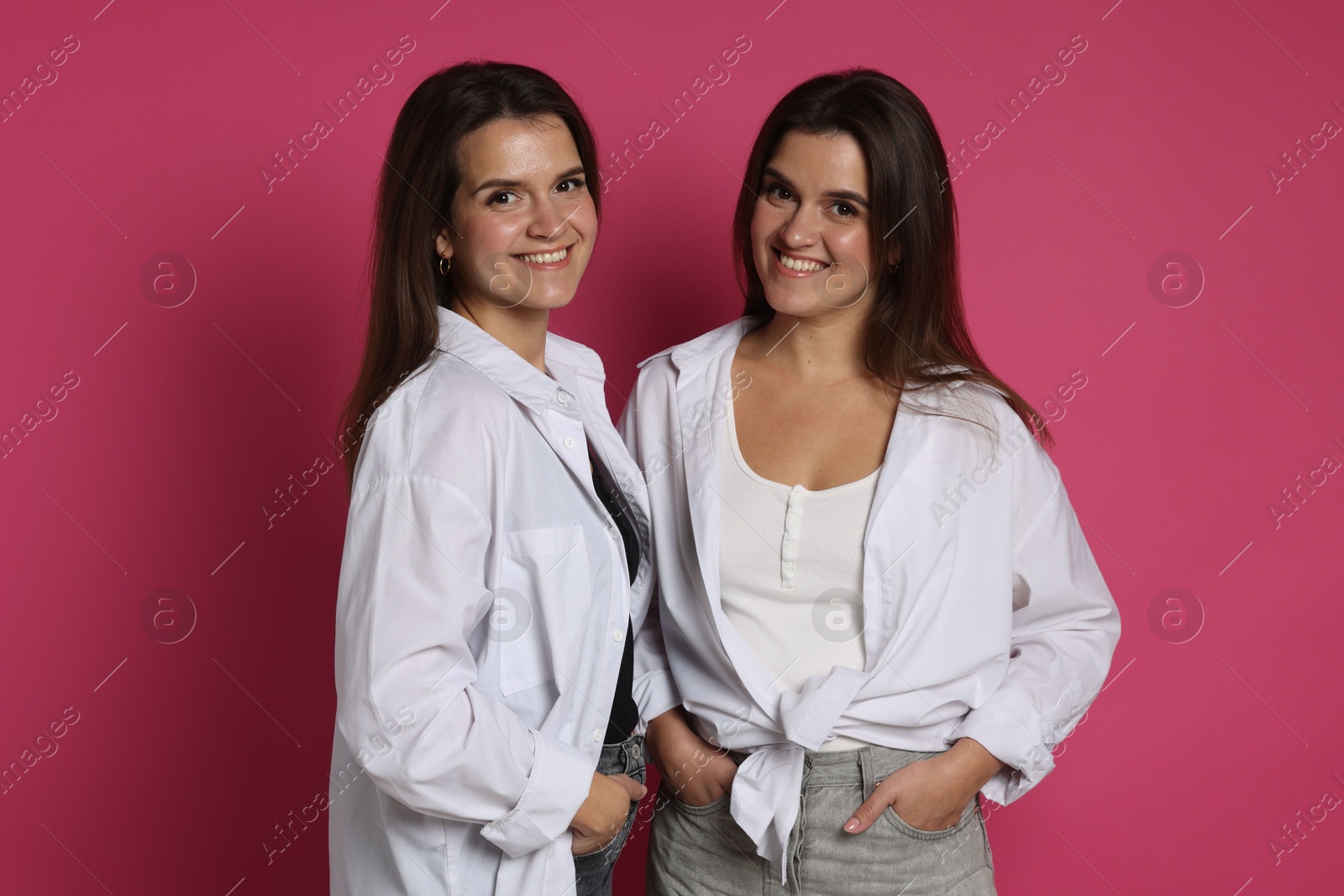 Photo of Portrait of beautiful twin sisters on pink background