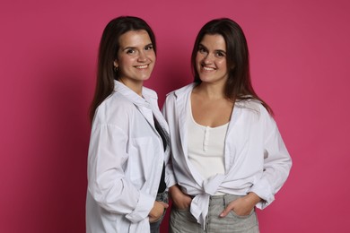 Photo of Portrait of beautiful twin sisters on pink background