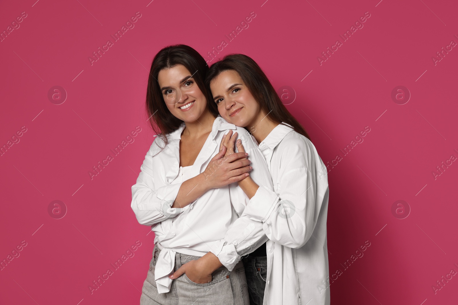 Photo of Portrait of beautiful twin sisters on pink background