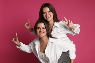 Photo of Beautiful twin sisters having fun on pink background