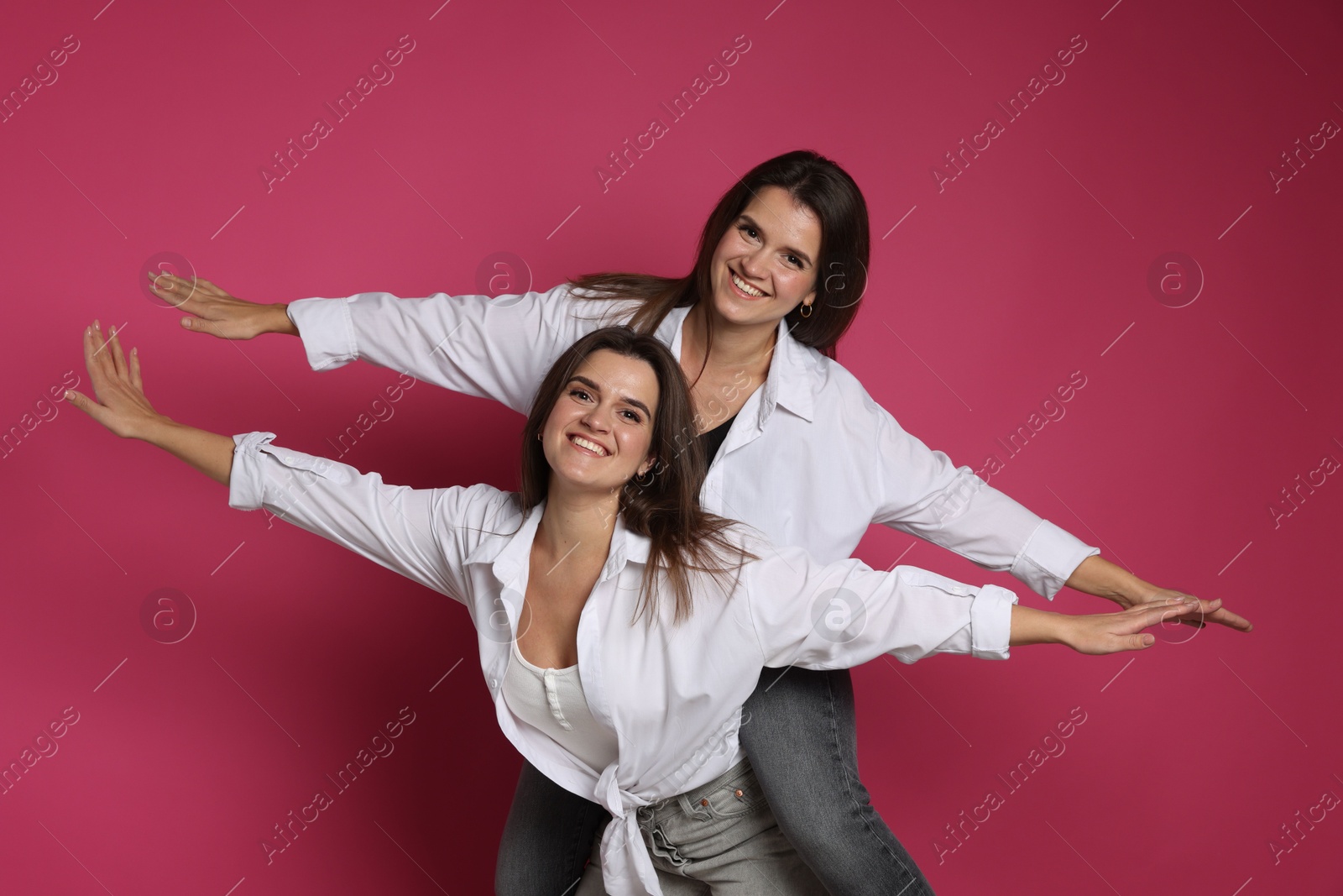 Photo of Beautiful twin sisters having fun on pink background