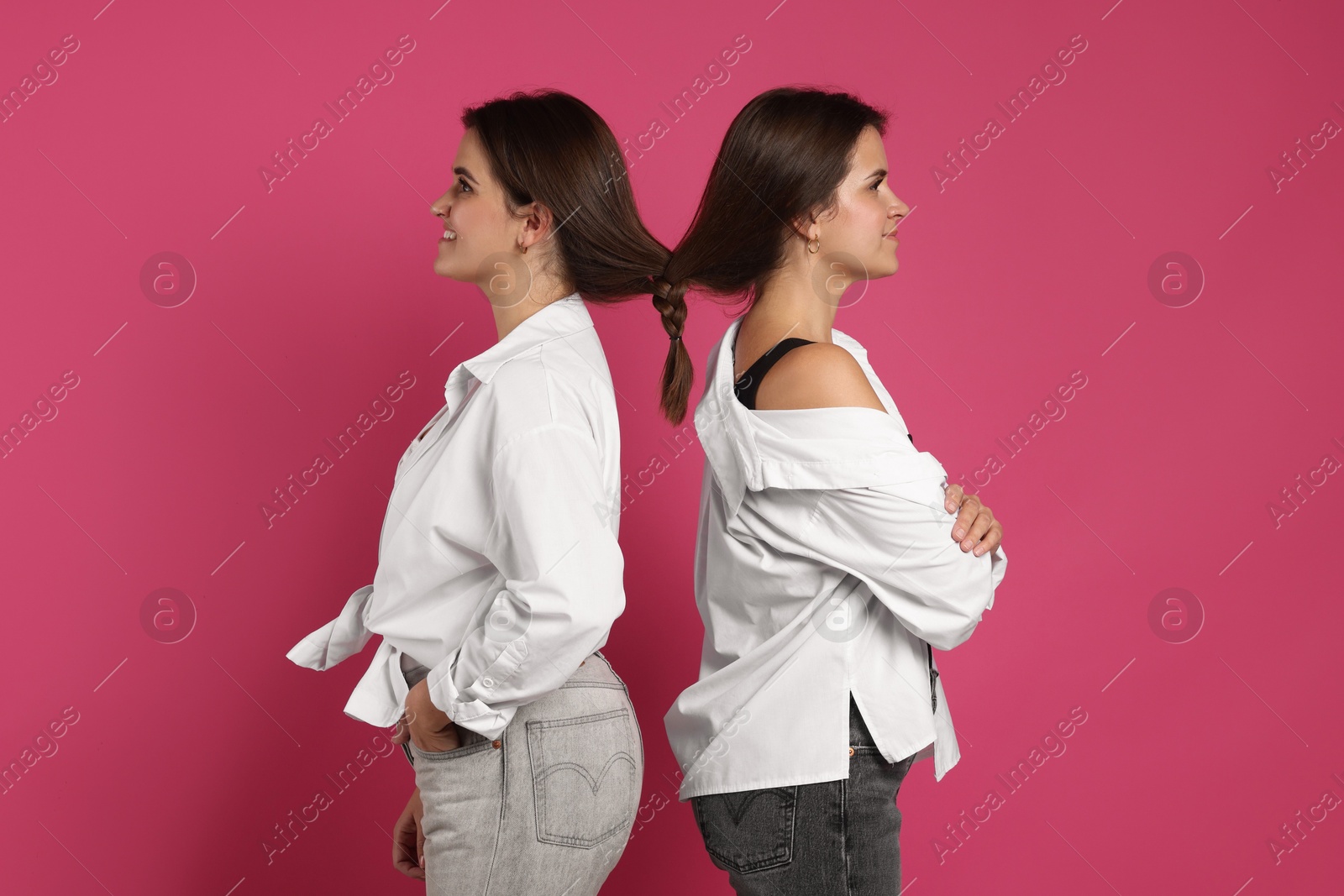 Photo of Portrait of beautiful twin sisters on pink background