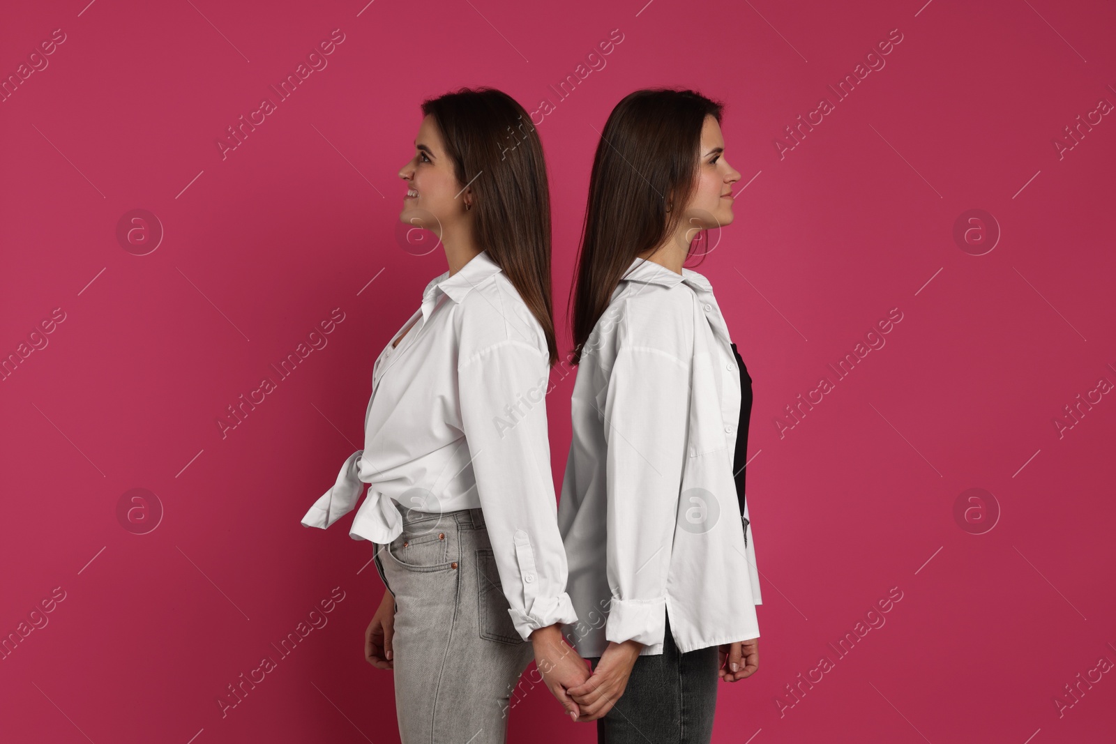 Photo of Portrait of beautiful twin sisters on pink background