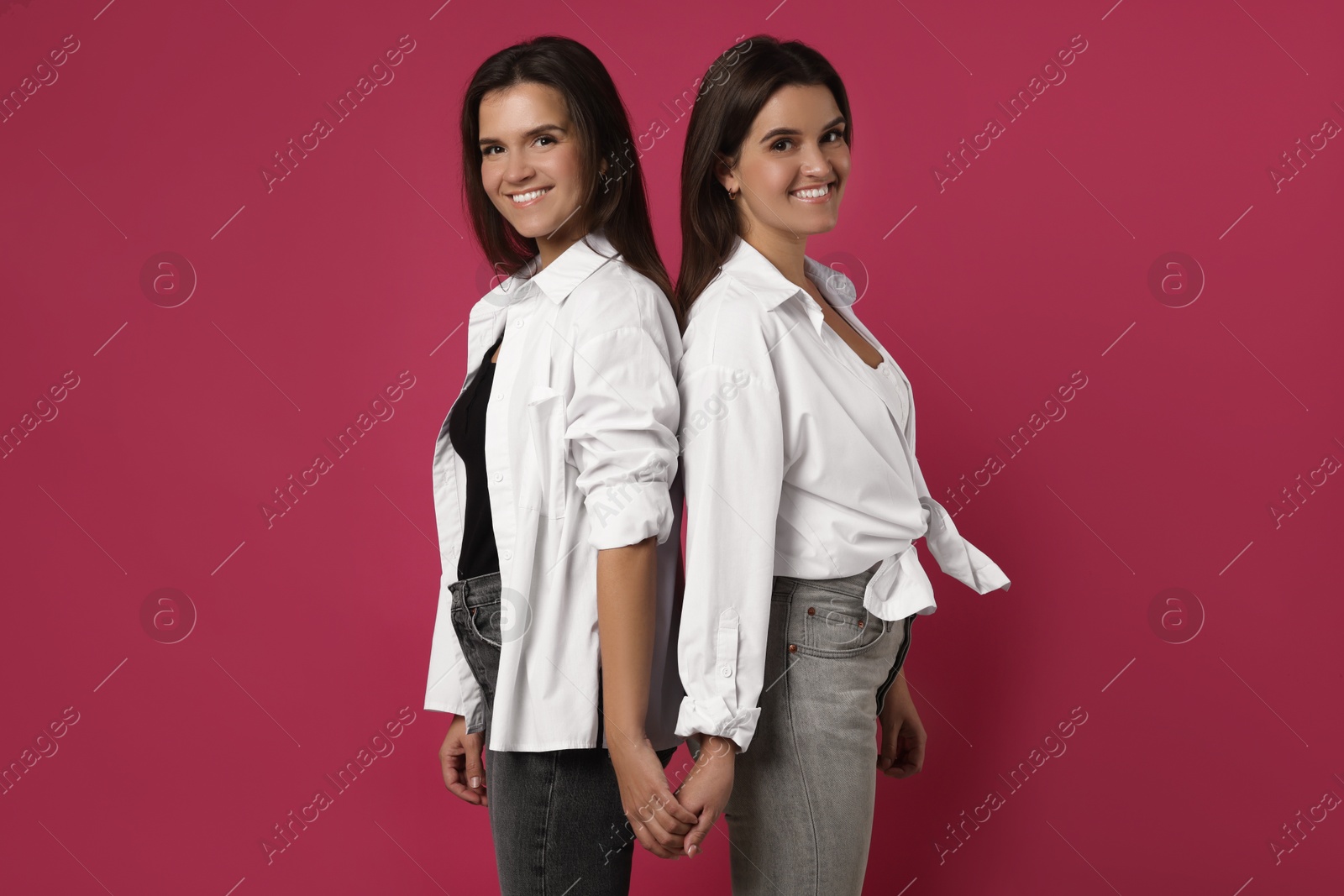 Photo of Portrait of beautiful twin sisters on pink background