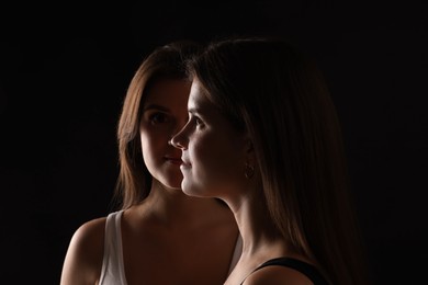 Photo of Portrait of beautiful twin sisters on black background