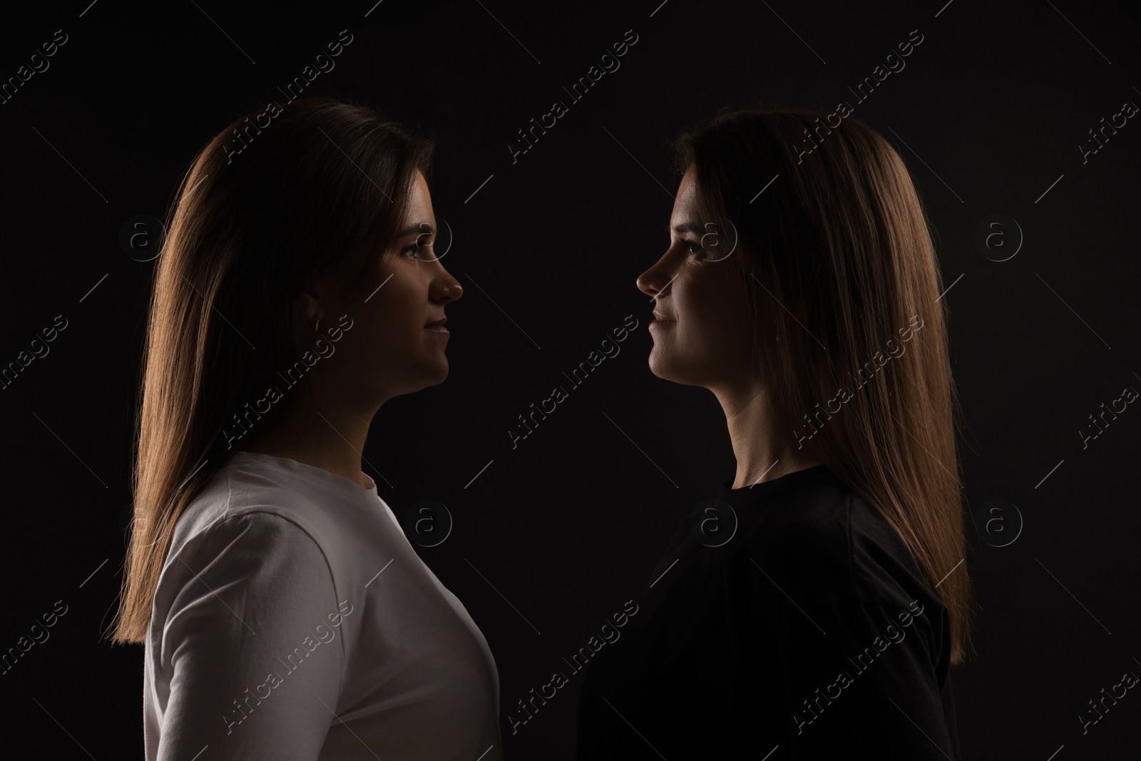 Photo of Portrait of beautiful twin sisters on black background