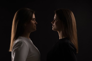 Photo of Portrait of beautiful twin sisters on black background