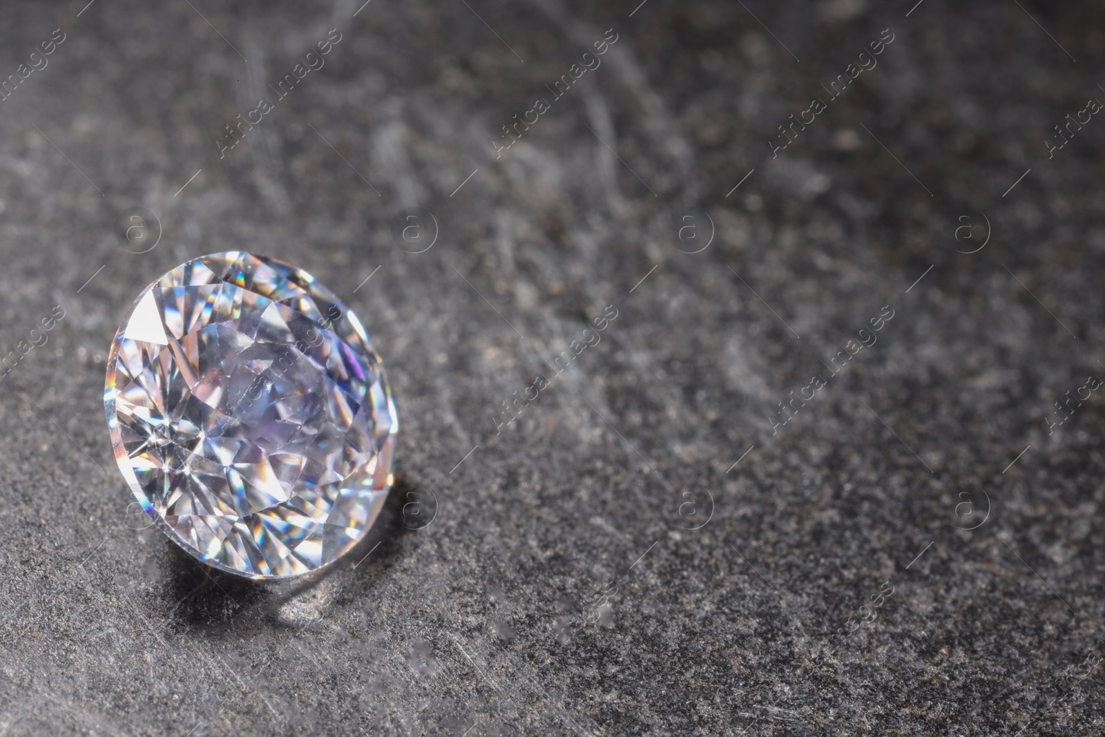 Photo of Beautiful shiny gemstone on stone, closeup. Space for text