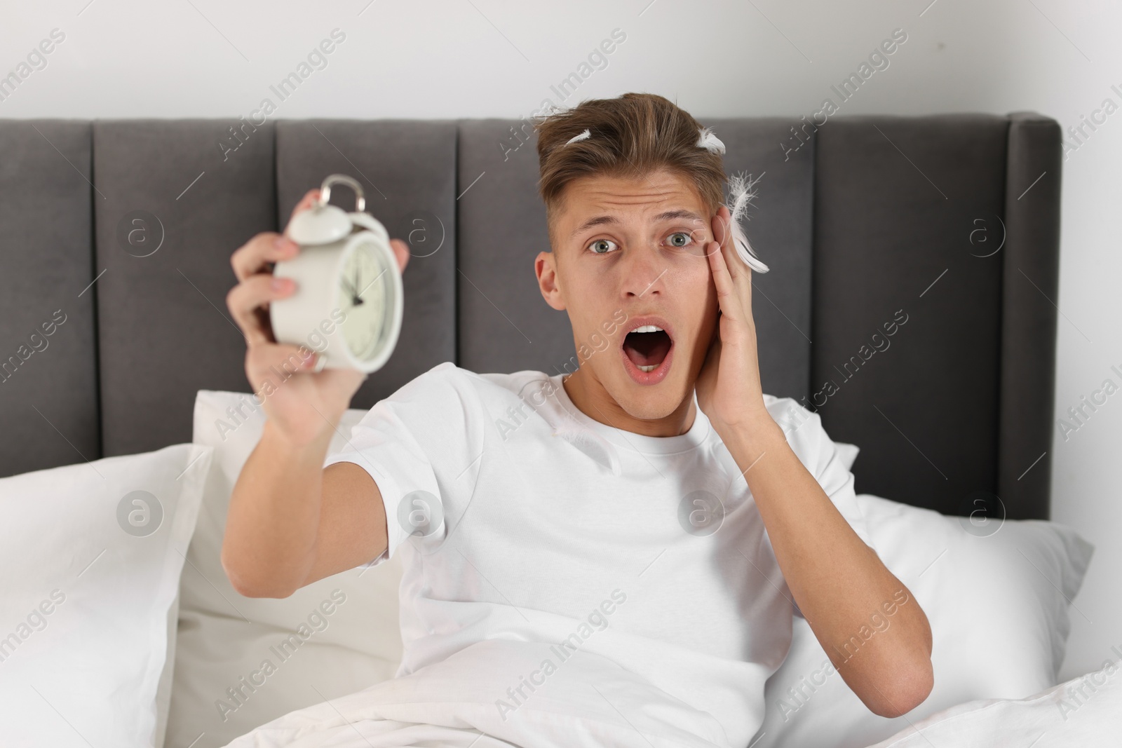 Photo of Overslept man with alarm clock in bed at home