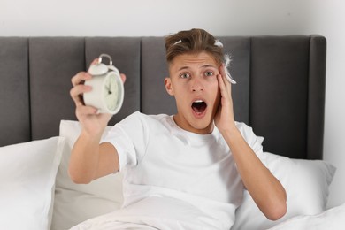 Photo of Overslept man with alarm clock in bed at home