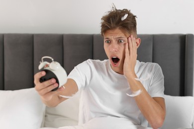 Photo of Overslept man with alarm clock in bed at home