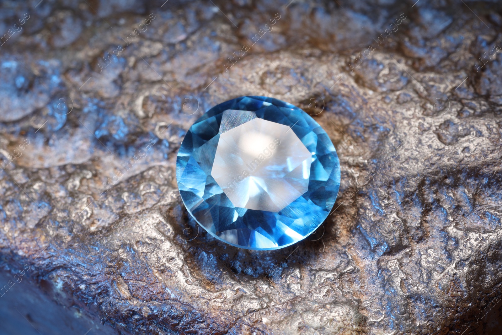 Photo of Beautiful shiny light blue gemstone on rock, closeup