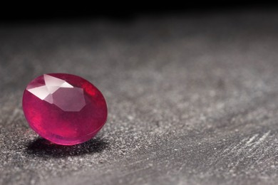 Photo of Beautiful shiny pink gemstone on stone, space for text