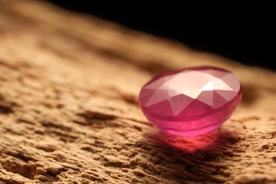 Photo of Beautiful shiny pink gemstone on stone, closeup. Space for text