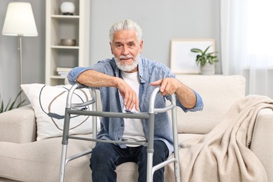 Photo of Senior man with walking frame on sofa at home