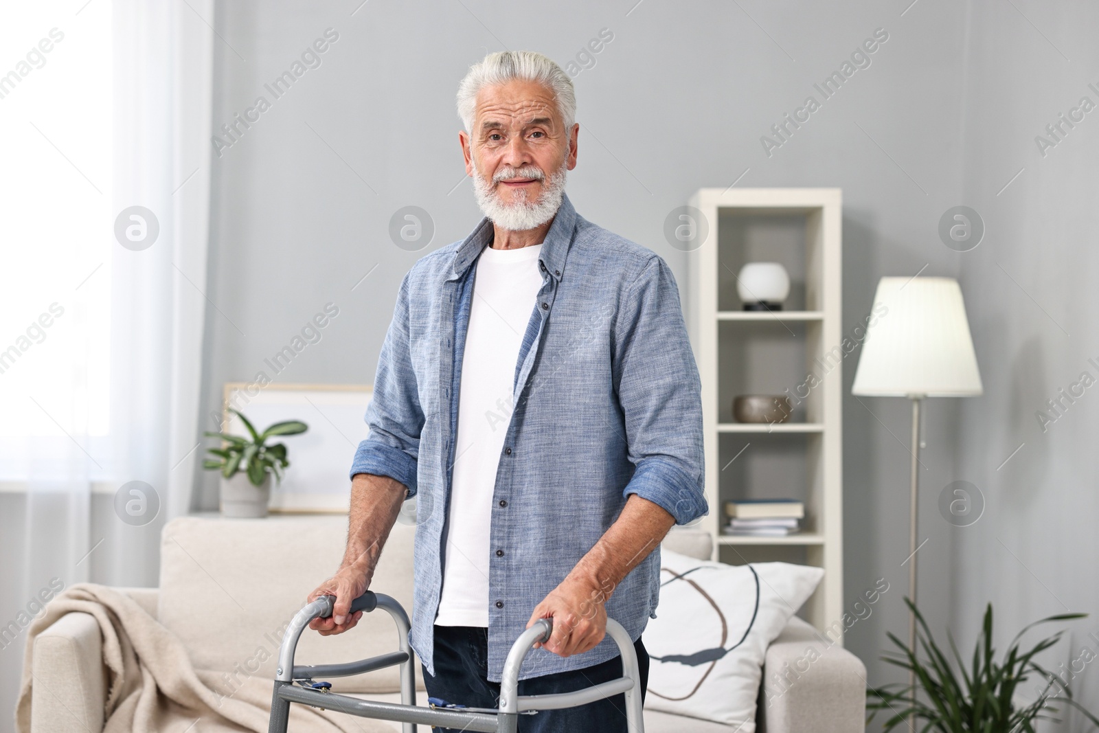 Photo of Senior man using walking frame at home