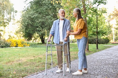 Photo of Senior couple with walking frame in park, space for text