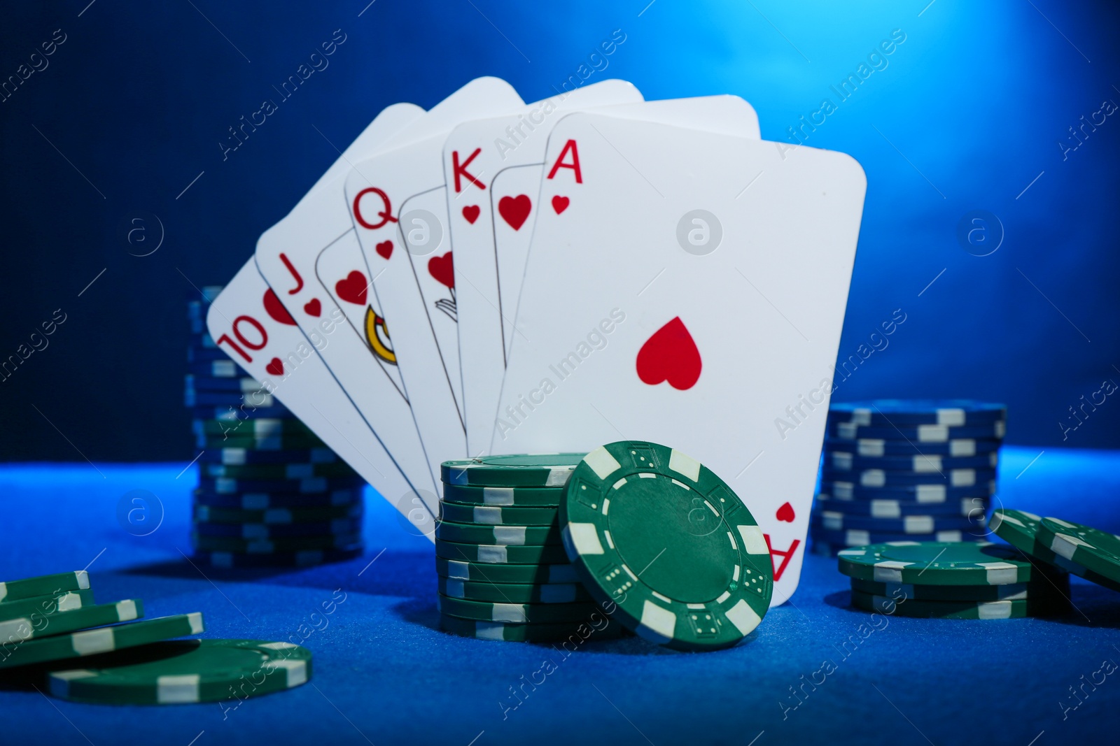 Photo of Poker chips and playing cards on blue table, closeup