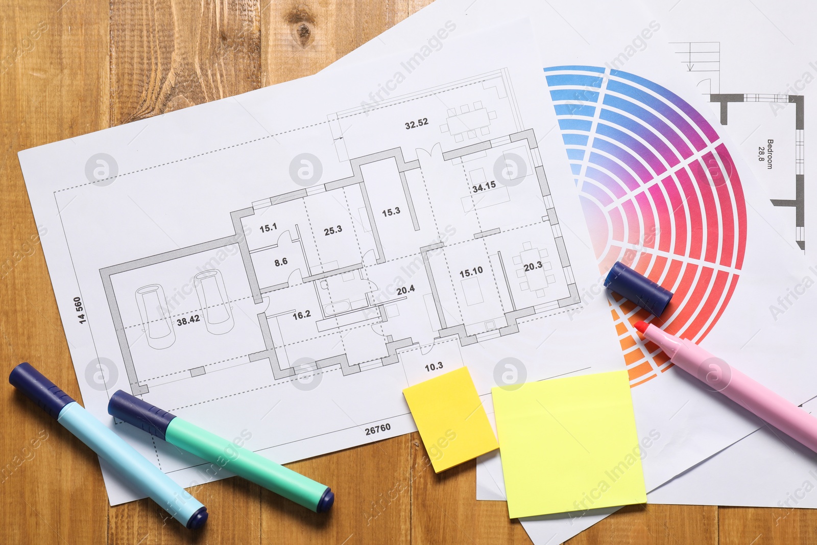 Photo of Designer's workplace with house plan, color palette and stationery on wooden table, flat lay