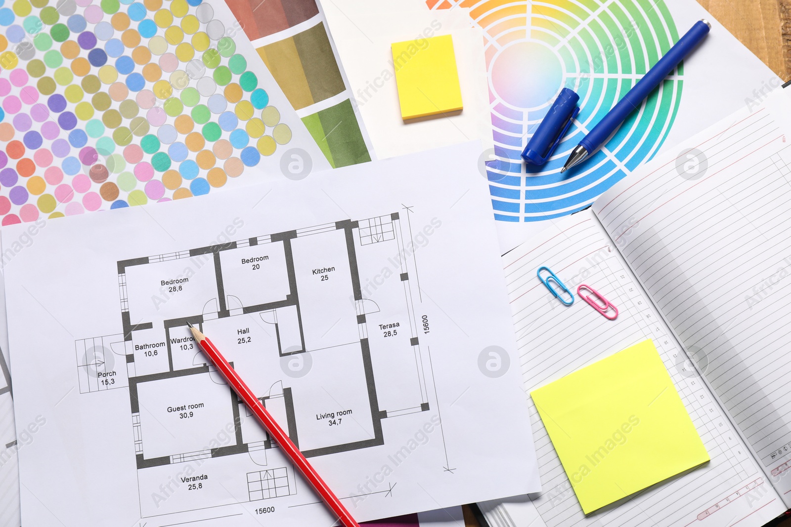 Photo of Designer's workplace with house plan, color palettes and stationery on table, flat lay