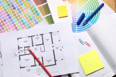 Photo of Designer's workplace with house plan, color palettes and stationery on table, flat lay