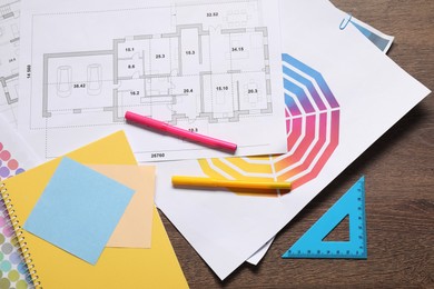 Photo of Designer's workplace with house plans, color palettes and stationery on wooden table, flat lay