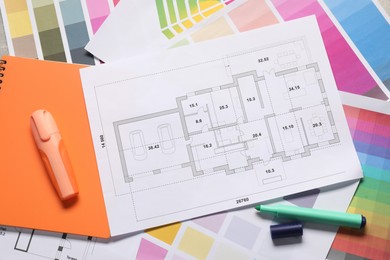 Photo of Designer's workplace with house plans, color palettes and stationery on table, top view