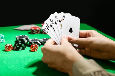 Photo of Poker game. Woman with playing cards at green table, closeup