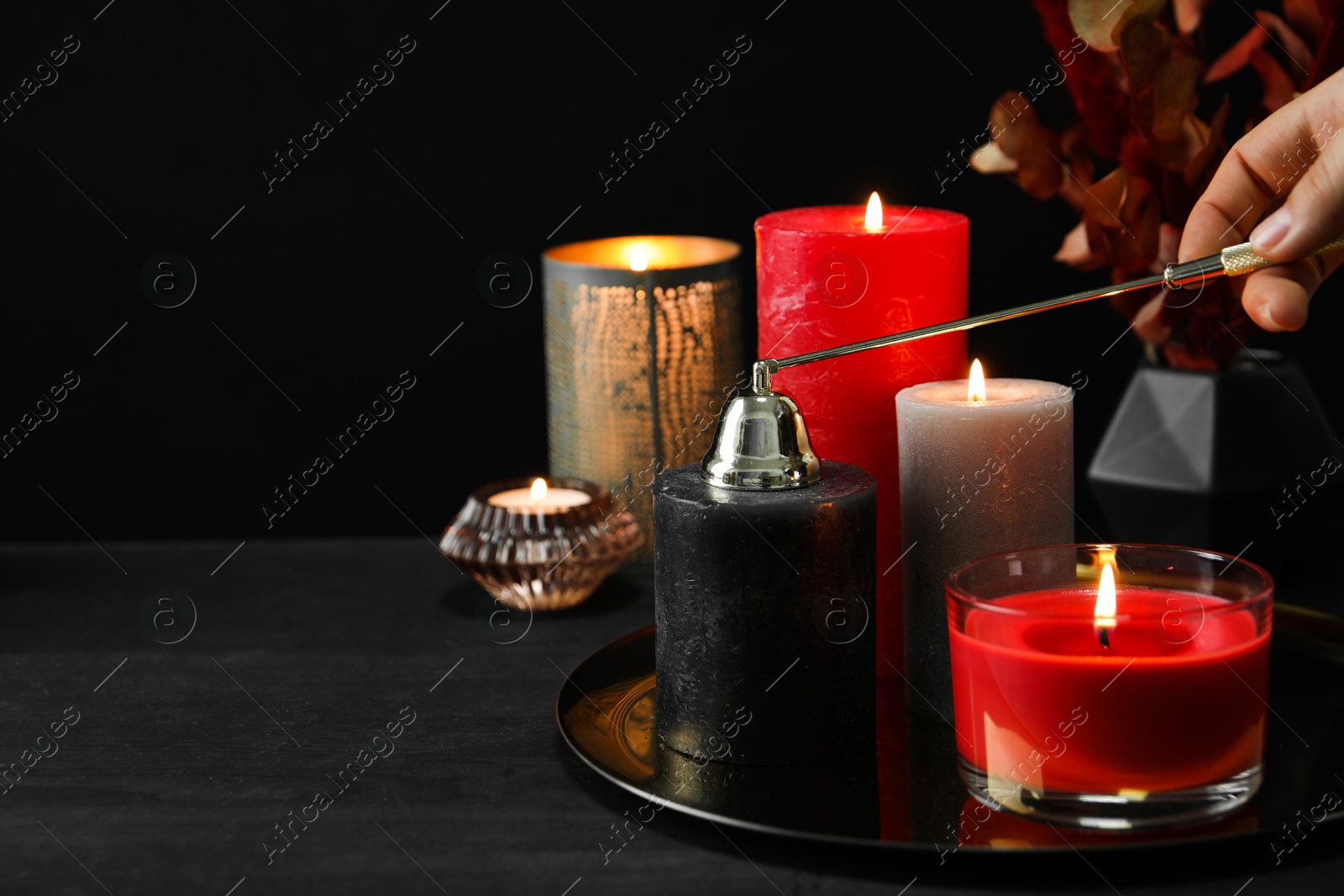 Photo of Woman with beautiful burning candles and decor on black table, closeup. Space for text