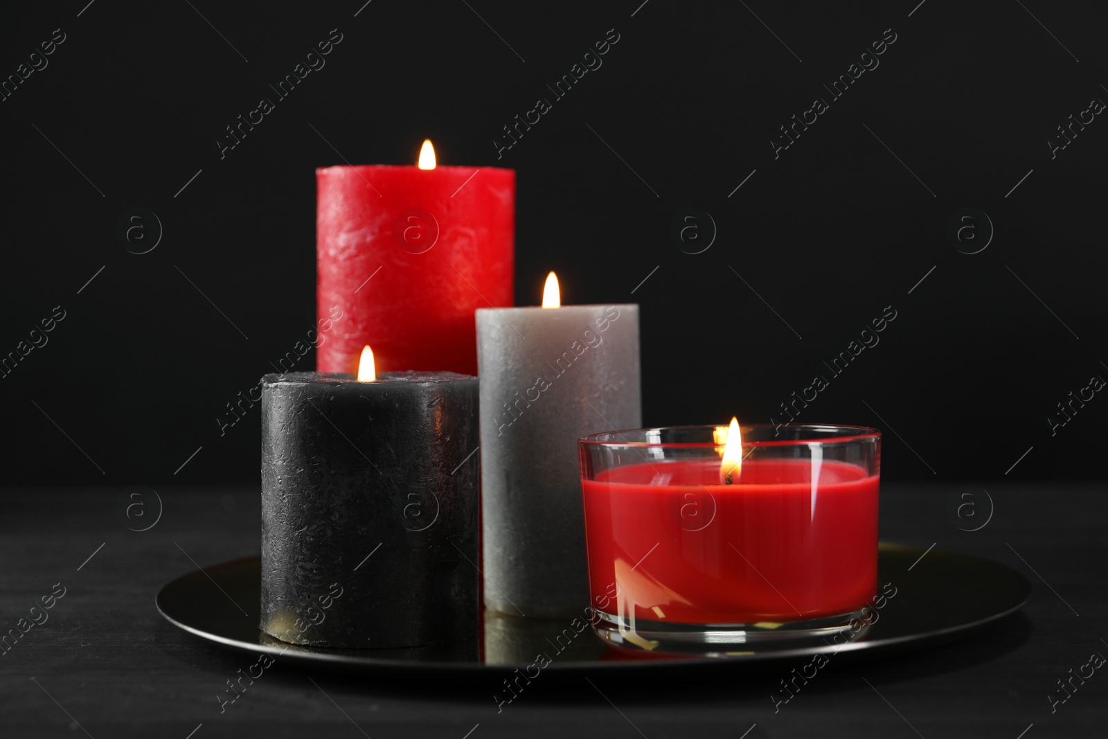 Photo of Beautiful burning candles on black table, closeup