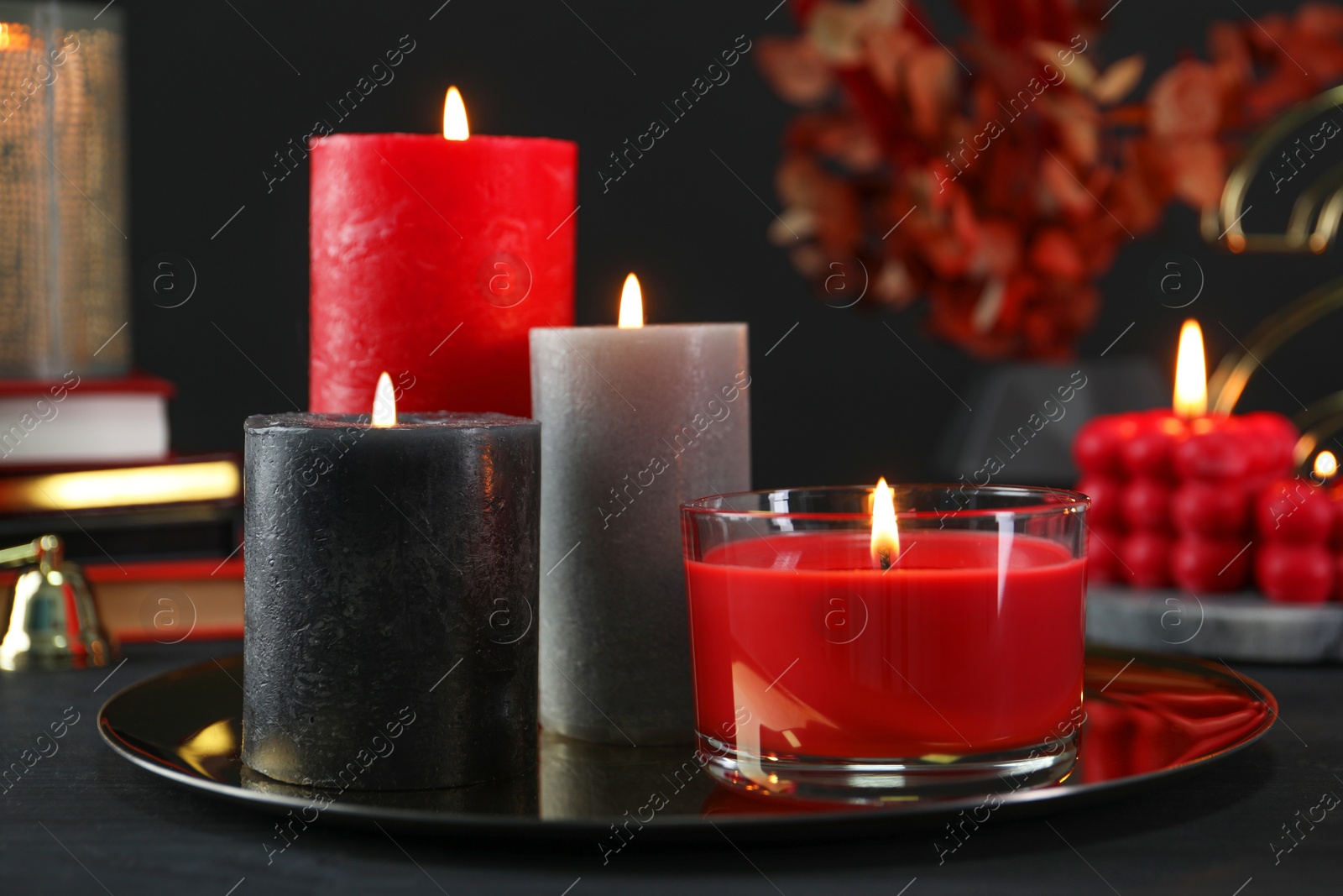 Photo of Beautiful burning candles and decor on black table, closeup