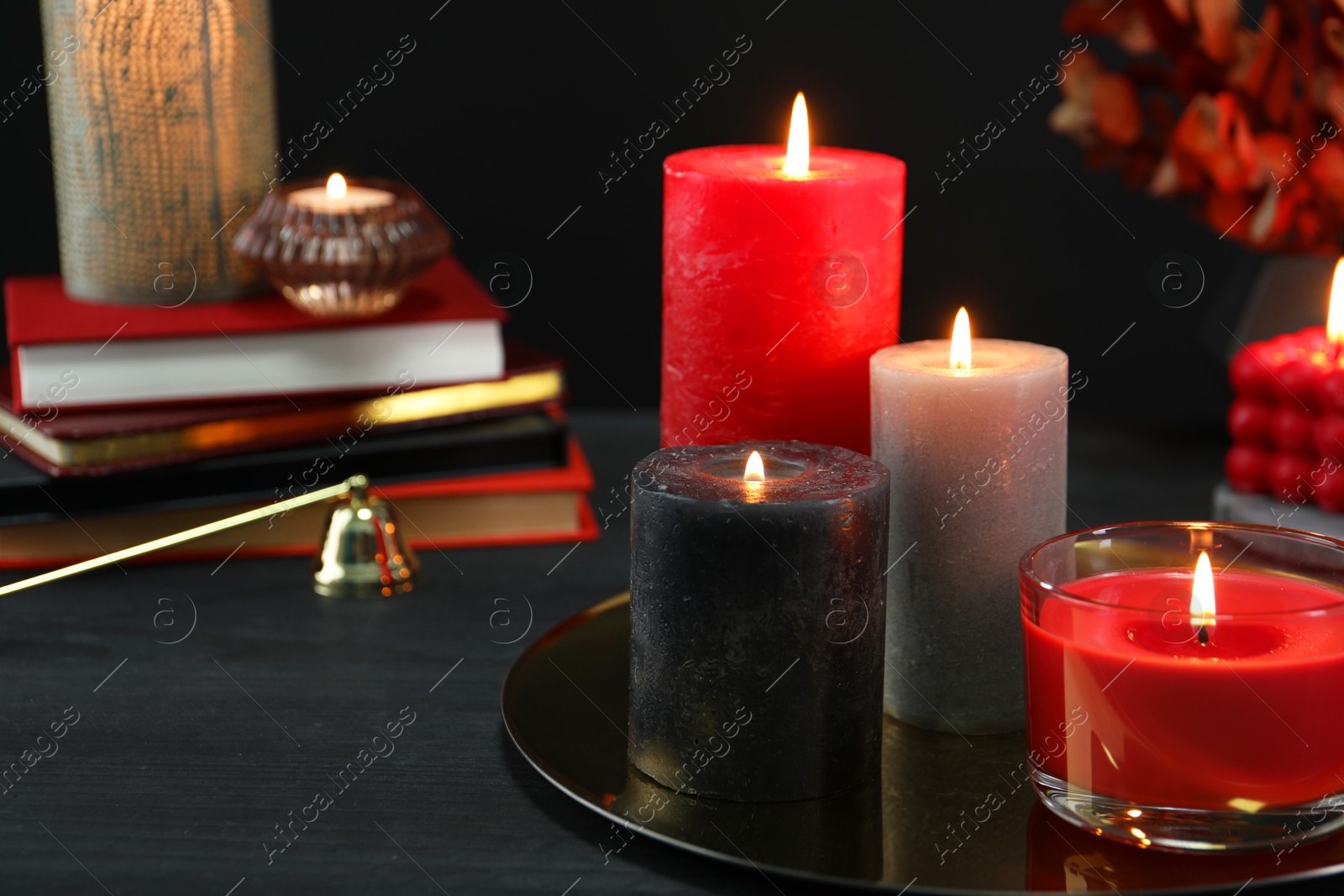 Photo of Beautiful burning candles and decor on black table, closeup