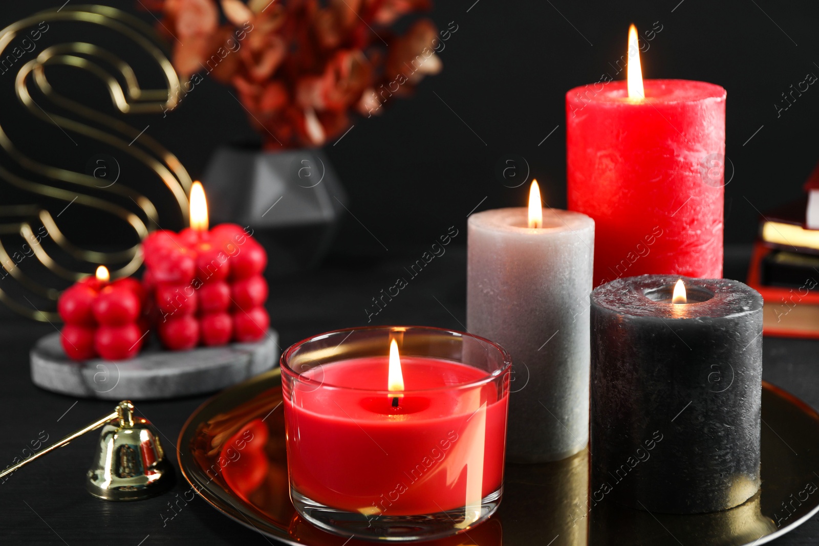 Photo of Beautiful burning candles and decor on black table, closeup