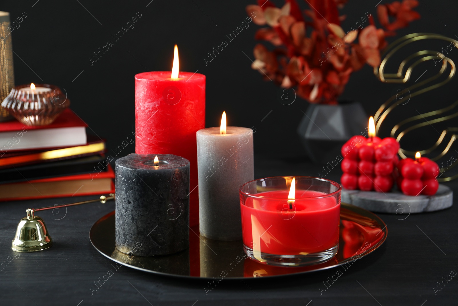 Photo of Beautiful burning candles and decor on black table, closeup