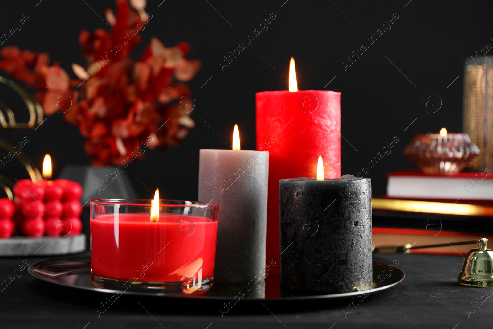 Photo of Beautiful burning candles and decor on black table, closeup