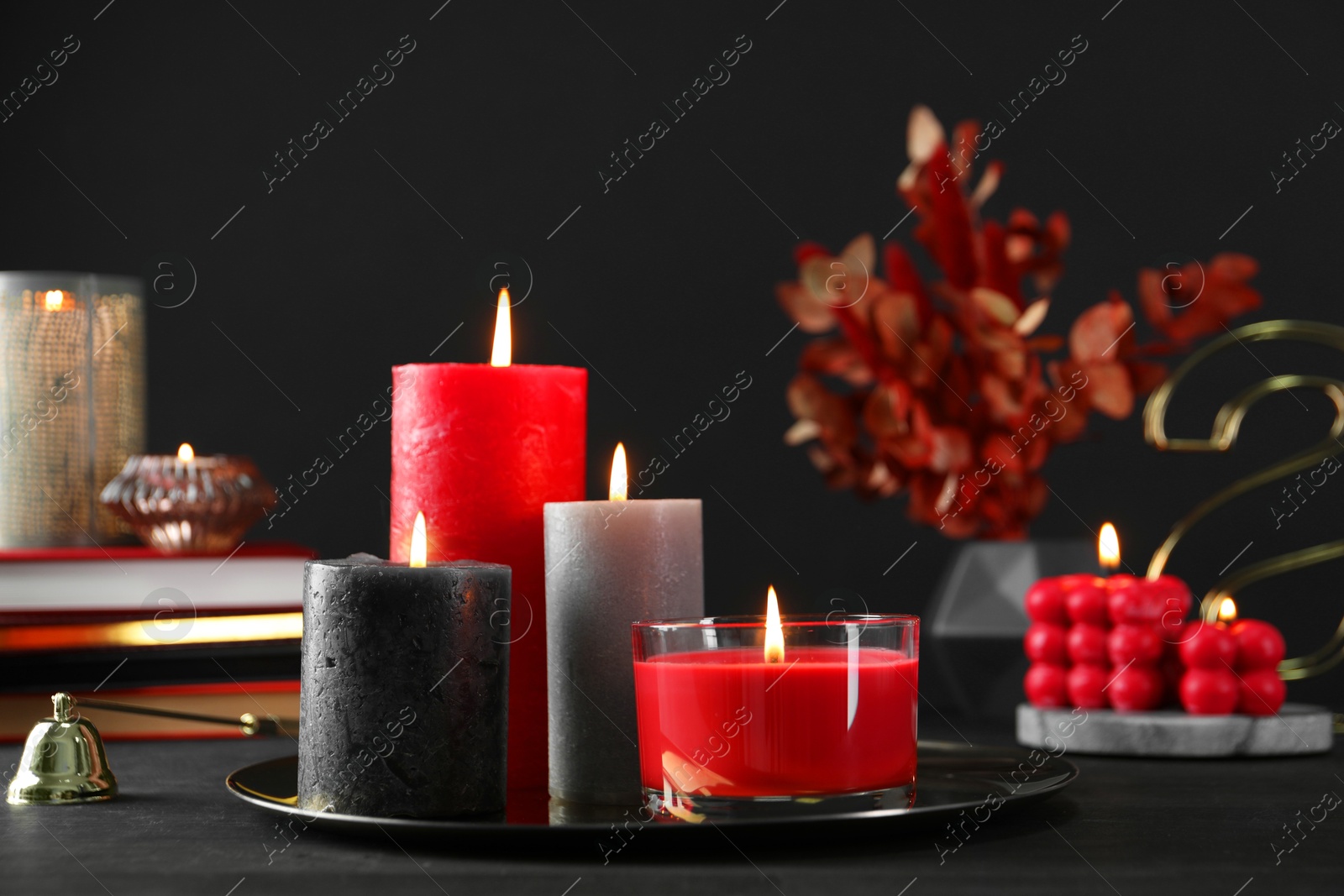 Photo of Beautiful burning candles and decor on black table