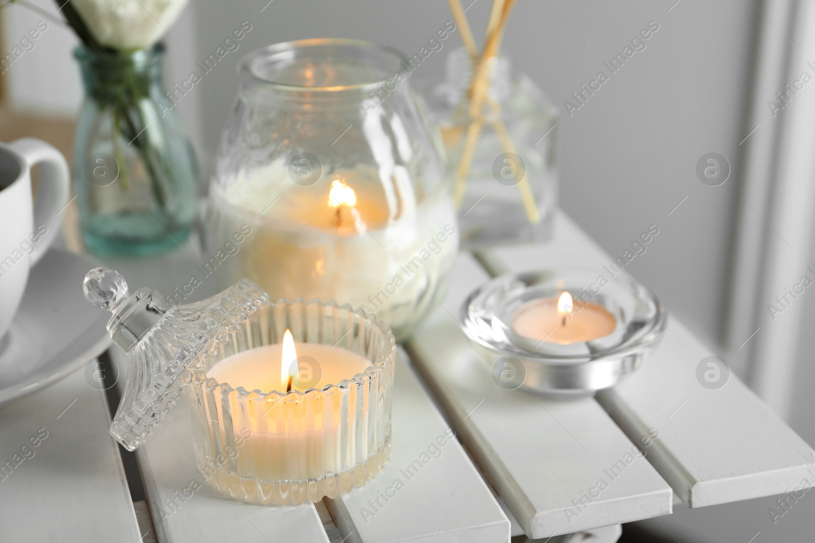 Photo of Beautiful burning candle on white wooden table, closeup