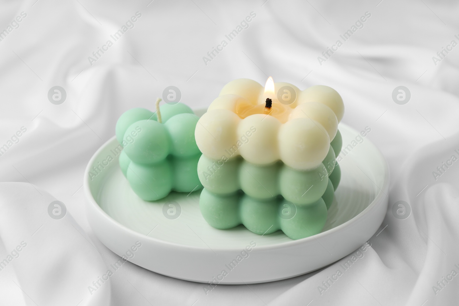 Photo of Stylish bubble candles on white cloth, closeup