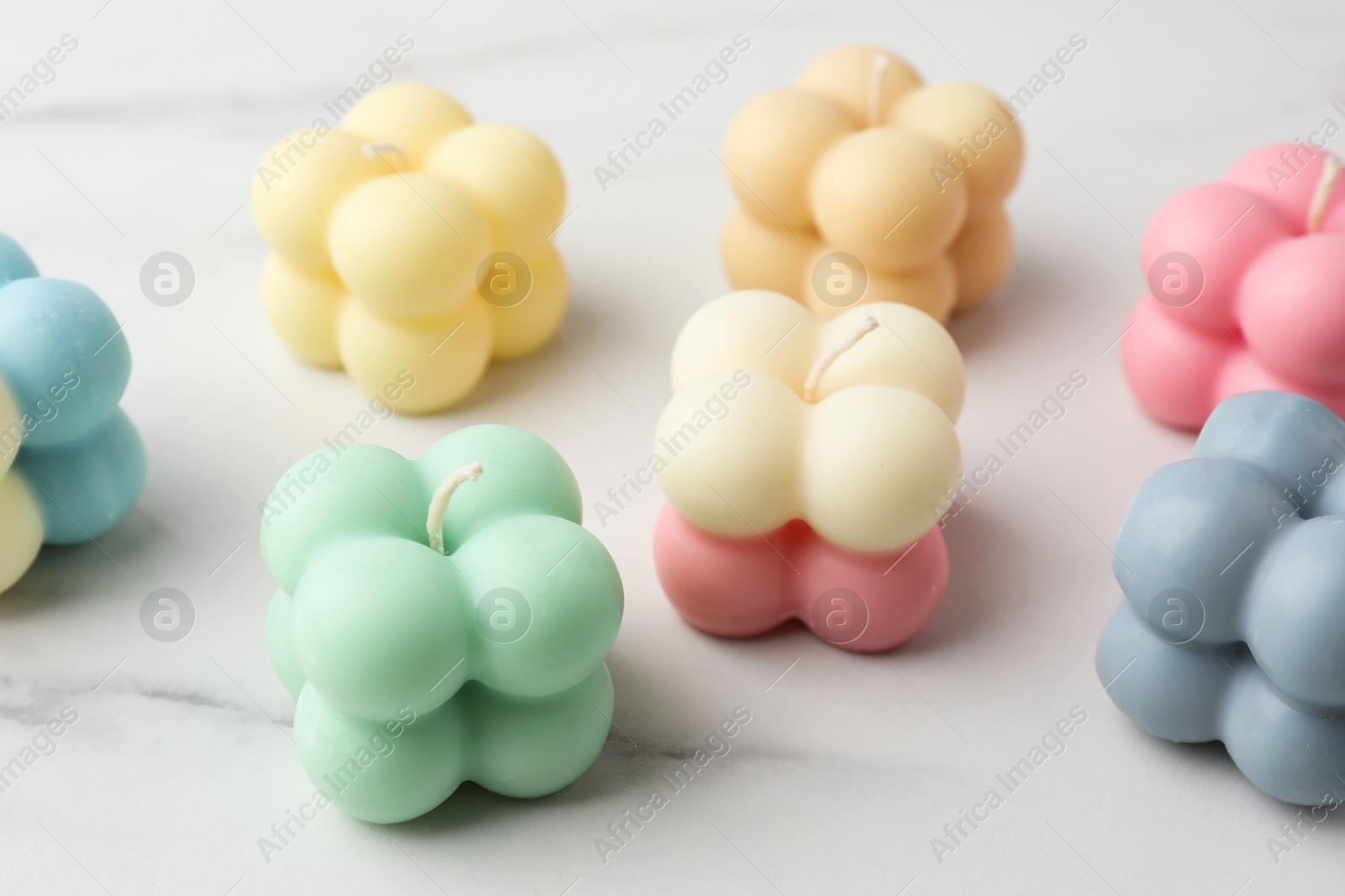 Photo of Different stylish bubble candles on white marble table, closeup